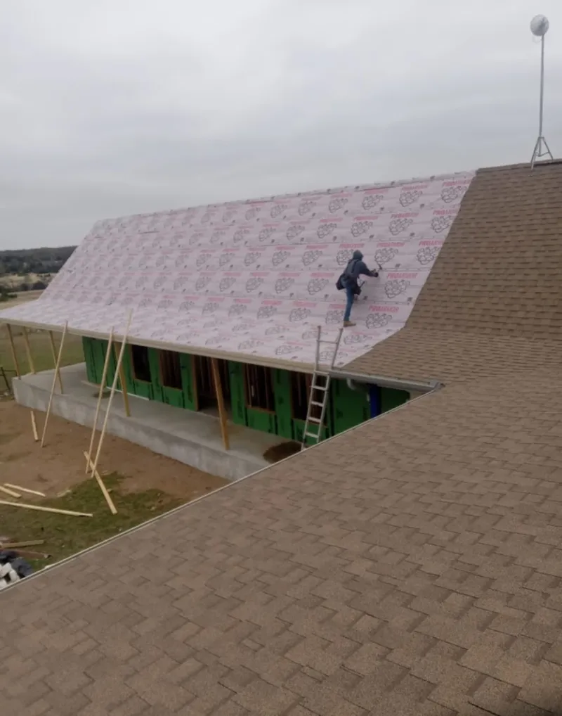Worker preparing underlayment for a metal roof installation in New Carlisle